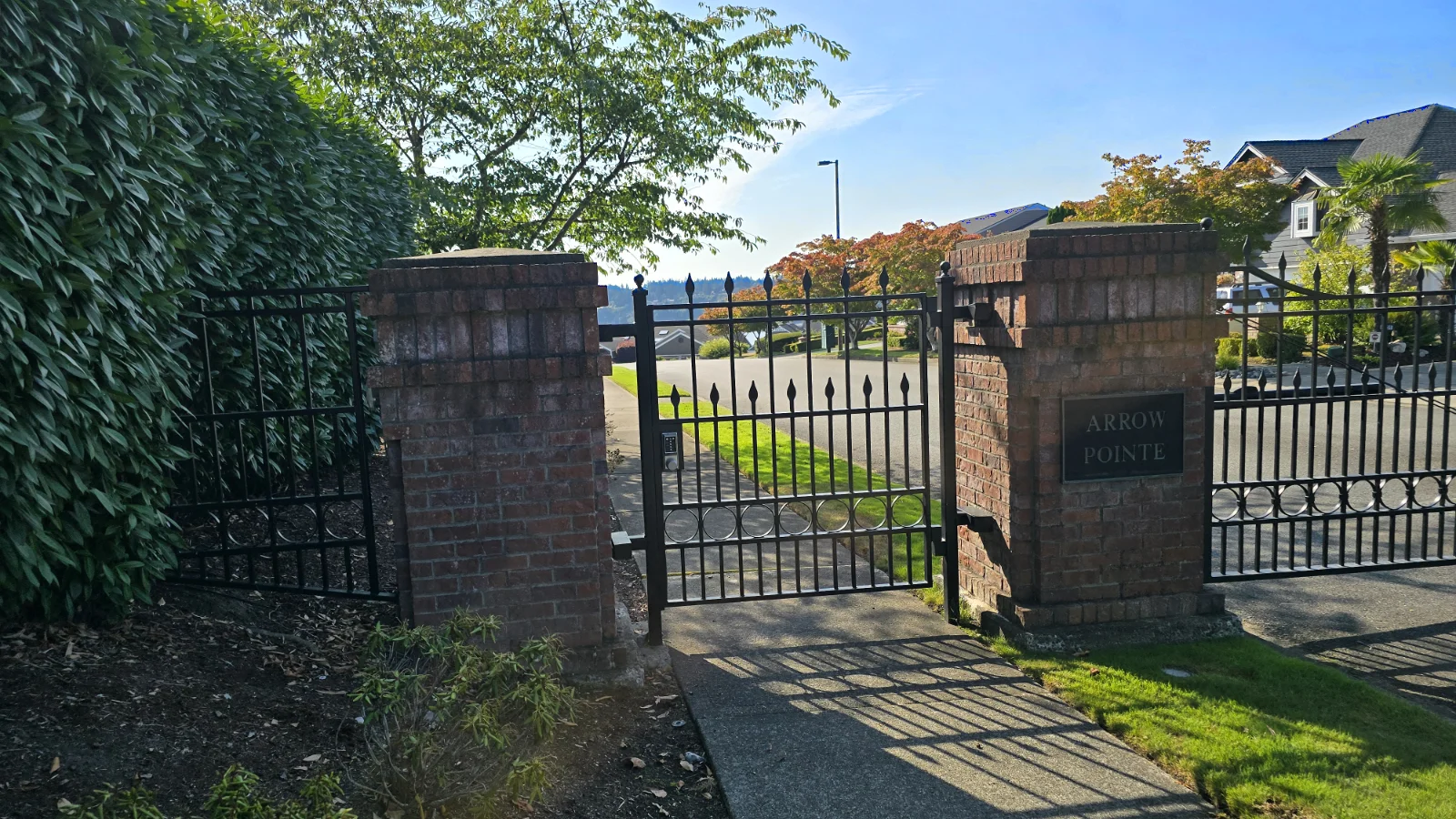 Locked wrought iron gate supported by brick pillars across a sidewalk