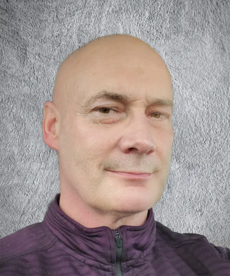 S. A. Weigle headshot against gray wall, looking at camera with slight smile